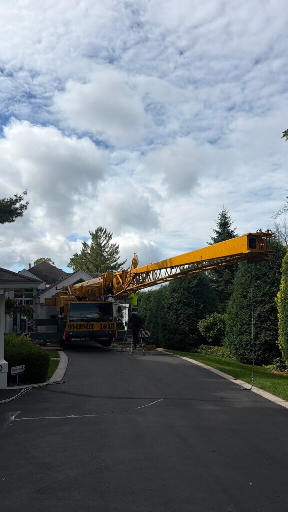 Liebherr mobile crane extended over a home during a tree removal by Statement Tree Care in the Minneapolis area